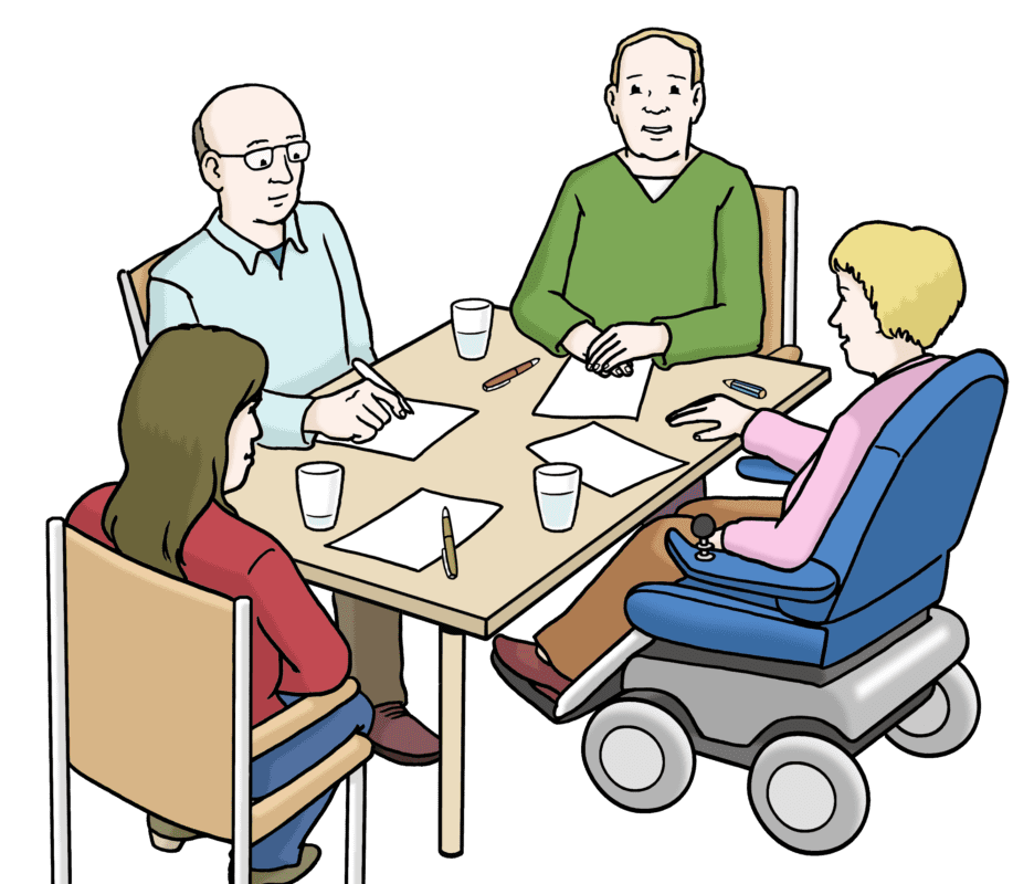 Vier Personen versammelten sich um einen Tisch, drei sitzen auf Stühlen und eine Person im Rollstuhl. Sie sprechen, vor ihnen stehen Papiere und Gläser. Eine Person gestikuliert beim Sprechen.